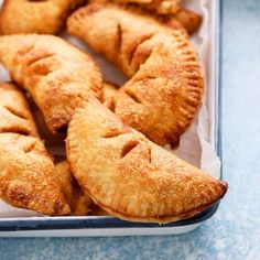 several pastries in a tray on a blue tablecloth with one cut out and the other half eaten