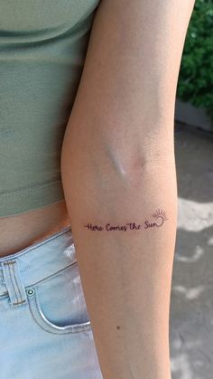 a woman with a tattoo on her arm that says, home comes the sun