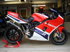 a red, white and blue motorcycle parked in a garage