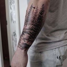 a man with a forest tattoo on his arm