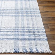 a blue and white rug with fringes on the floor in front of a wooden floor