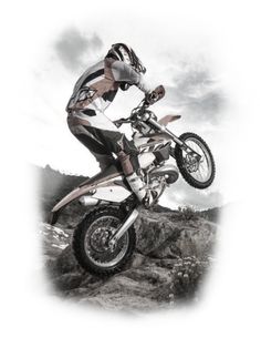 a man riding on the back of a dirt bike over a rocky hill with mountains in the background