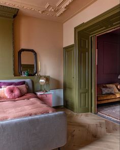 a bed sitting in a bedroom next to a green door and pink pillow on top of it