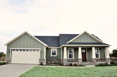 a gray and white house with two garages on the side of it in front of a green lawn