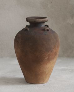 a brown vase sitting on top of a white table