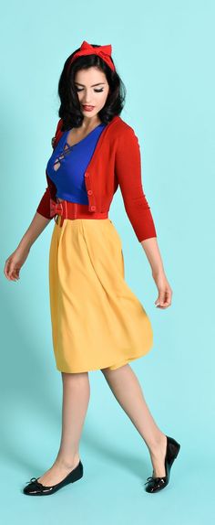 a woman in a red cardigan, yellow skirt and black shoes is posing for the camera