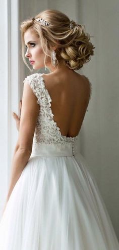 a woman in a wedding dress looking out the window with her back to the camera