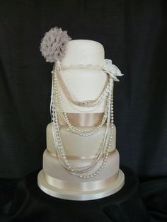 a three tiered wedding cake with pearls and flowers