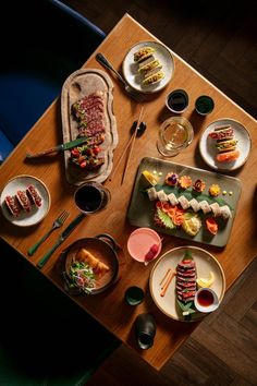 a wooden table topped with plates and bowls filled with different types of food on top of it