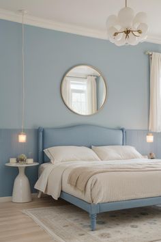 a bedroom with blue walls, white bedding and a round mirror on the wall