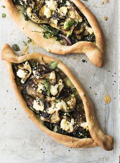 two pizzas with toppings sitting on top of a table next to each other