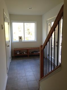 an empty hallway with tile flooring and wooden railing