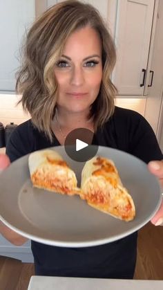 a woman holding a plate with two slices of pizza on it