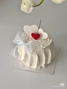 a cake with white frosting and a red heart on top