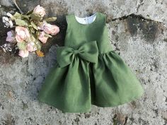 An adorable green linen dress, a perfect choice for baby's first Christmas. The linen fabric is soft and comfortable, and the back button closure adds a sweet detail, to this baby girl special occasion dress. The dress is made of a green light weight linen fabric, and the bodice is lined with a cotton fabric. The skirtpart is unlined. The waist is decorated with a big bow in the same green fabric and sash tails are sewn into the side seams. By tying the sash tails to a cute bow at the back, the St Patricks Day Dress, Baby Holiday Dress, Baby Christmas Dress, Baby Special Occasion Dress, Green Linen Dress, Toddler Christmas Dress, Christmas Dress Baby, Holiday Outfits Christmas