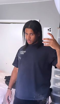 a man taking a selfie with his cell phone in front of him and wearing a black t - shirt