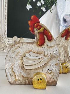 two chicken figurines sitting on top of a table next to a framed photo