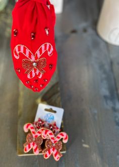 two red and white candy canes are on a wooden table next to a bag