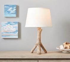 a table lamp sitting on top of a wooden dresser next to a bowl and plate