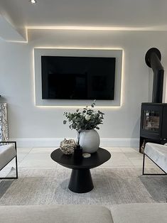 a living room with white furniture and a flat screen tv mounted on the wall above it