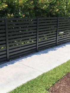 a black fence is next to a sidewalk and grass in front of it on a sunny day