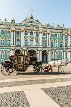 a horse drawn carriage in front of a large blue and white building with gold trim