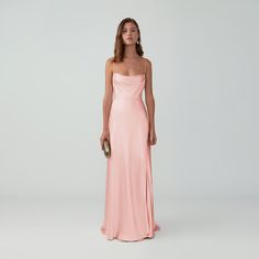 a woman in a long pink dress is standing with her hands on her hips and looking off to the side