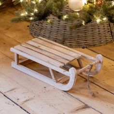 a wooden sled sitting on top of a wooden floor next to a christmas tree