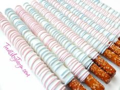 there are many candy sticks lined up on the white tablecloth with pink, blue and white frosting