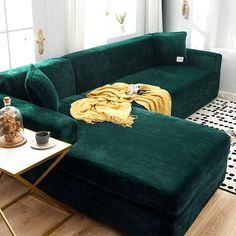 a large green couch sitting on top of a wooden floor next to a white wall