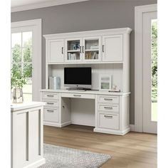 a white desk with drawers and a computer monitor on top of it in front of a window