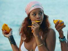 two beautiful young women eating fruit by the ocean