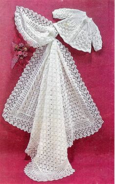 a white crocheted dress and bonnet on a pink background with flowers in the corner