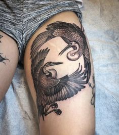 a woman laying on top of a bed next to a tattoo design that looks like two birds