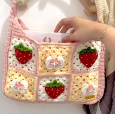 a crocheted strawberry purse being held by a woman