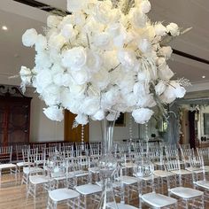 a large vase filled with white flowers sitting on top of a table covered in chairs