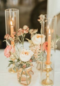 two vases with flowers and candles on a table