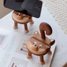 two wooden toy animals sitting on top of a table next to a cell phone holder