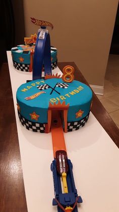 a cake shaped like a race track with cars around it on a white countertop