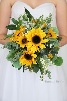 a bride holding a bouquet of sunflowers and greenery