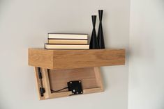 a wooden shelf with two black vases on it and books in the bottom drawer