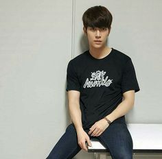 a young man sitting on top of a white bench wearing a black shirt and jeans