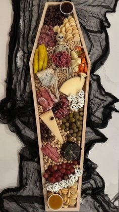 a wooden tray filled with different types of food on top of a black cloth covered wall