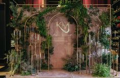 a stage set up for an event with greenery on the walls and arches in the center