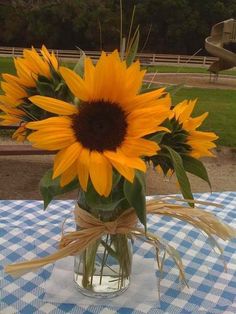 a vase with sunflowers in it sitting on a blue and white table cloth