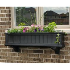 a window box filled with flowers next to a brick wall