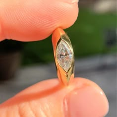 a close up of a person's hand holding a ring with a diamond on it