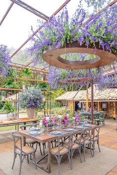 an outdoor dining area with purple flowers hanging from the ceiling