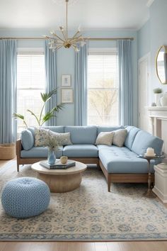 a living room with blue couches and curtains on the windowsills, a round coffee table in front of a fireplace