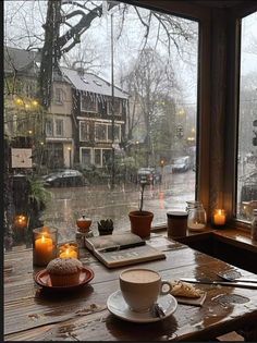 a cup of coffee sitting on top of a wooden table next to a window covered in rain